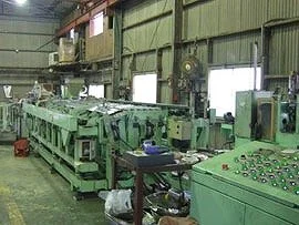 緑色の加工機や制御盤が並ぶ、工場内の樹脂コーティング加工ライン